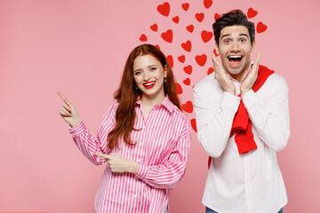 Wall Mural - Young shocked couple two friends woman man 20s wear casual shirt point index finger aside on copy space area hold face isolated on plain pink background Valentine's Day birthday holiday party concept