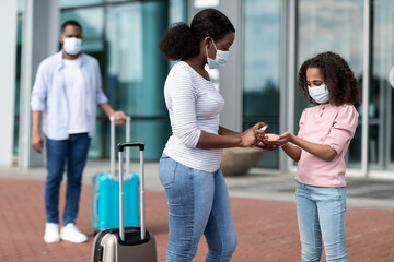 Wall Mural - Black family traveling, mom using sanitizer on daughter's hands