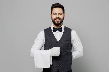 Wall Mural - Young smiling fun barista male waiter butler man 20s wear white shirt vest elegant uniform gloves work at cafe hold towel isolated on plain grey background studio portrait Restaurant employee concept