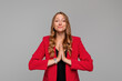 Coy young blonde woman begging for help, apologizing, say please with beg pray gesture, need something, standing in red blazer against gray background