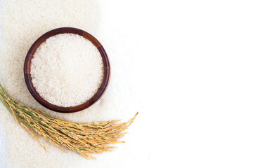 Jasmine or white rice in a wooden bowl with ears of rice isolated on white background, top view, copy space