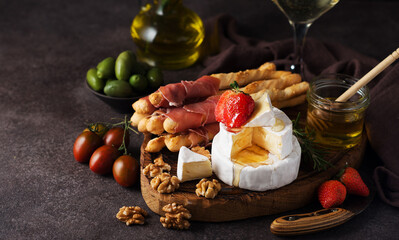 Brie cheese, camembert, grissini, jamon, wine, nuts, honey. Snacks for wine.