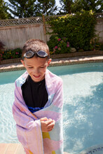 Smiling Boy (8-9) Wrapped In Towel Standing On Poolside