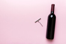 One Bottle Of Red Wine With Corkscrew On Colored Table. Flat Lay, Top View Wth Copy Space