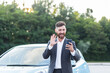© Liubomir - Happy businessman car salesman inspects the car online with a video call, and an application on the phone, a man has fun selling a car