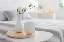 Cup Of Coffee And White Flowers In Vase On Table In Bedroom