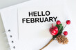 © Volha - hello february greeting card, text on a white card with a notepad on the table