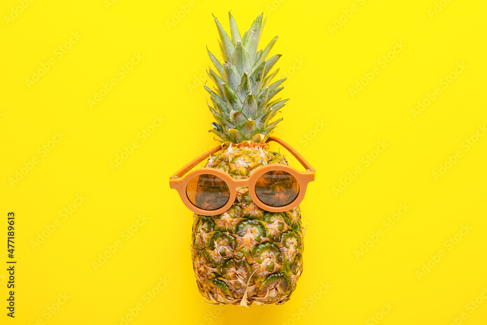 Fresh pineapple in sunglasses on yellow background