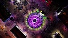 State Fair At Night Time Aerial View. Drone Flight Over Blinking Neon Lights With Carousel Ride At Carnival In Portugal. 