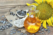 Sunflower oil in bottle on sunflower plant background, spoon with seeds and kernels on rustic wooden background, selective focus, shallow DOF
