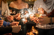 © Miljan Živković - Close up on hands of group of people holding glasses of wine and sparkles while toasting and celebrating indoor focus on glass of wine birthday or new year celebration concept