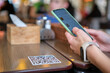 © bilanol - Closeup of guest hand ordering meal in restaurant while scanning qr code with mobile phone for online menu