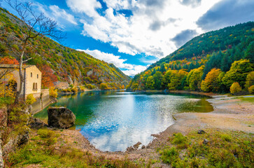 Wall Mural - Villalago (Abruzzo, Italy) - A view of medieval village in province of L'Aquila, situated in the gorges of Sagittarius, with Lago San Domenico lake, bridge and sanctuary. Here during autumn foliage