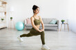 © Prostock-studio - Pretty young Indian lady making lunge, doing strength exercises, working out booty and legs muscles at home