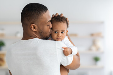 Father's Care. Young Black Dad Holding And Kissing Adorable Newborn Baby