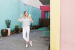 © Алина Бузунова - Pretty laughing caucasian woman with smartphone has good time outdoor. portrait of trendy millennial girl with blonde hair wears fashionable clothing