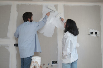 Young couple painting walls in their new house in construction.