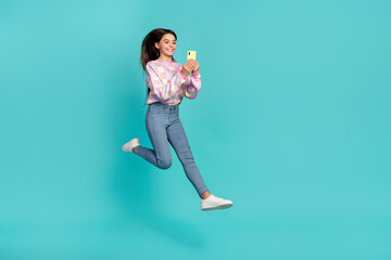 Poster - Full length body size view of pretty trendy cheery girl jumping using device isolated over bright teal turquoise color background