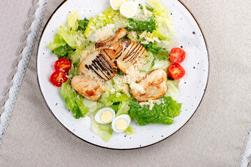 Wall Mural - Caesar salad with chicken on a white decorative plate. A classic salad. Top view