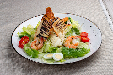 Wall Mural - Caesar salad with shrimp on a white decorative plate. A classic salad.