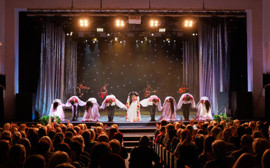 A collective of musicians, singers and dancers in gypsy costumes perform on stage.