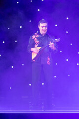 Wall Mural - Smoke and light on the stage. Male musicians balalaika player perform a concert on stage