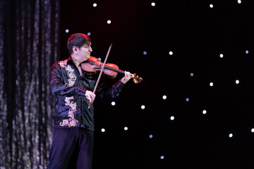 Smoke and light on the stage. Male musicians violinist perform a concert on stage