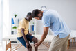 © LIGHTFIELD STUDIOS - young rehabilitologist pointing with hand at knee of african american patient