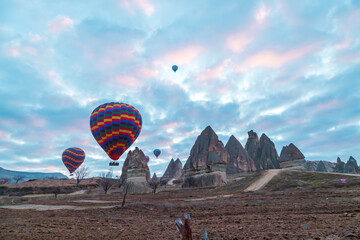 Hot air balloons flying over spectacular Cappadocia. Beautiful view of hot air balloons floating in sunrise blue sky over the mountain landscape of fairy chimneys