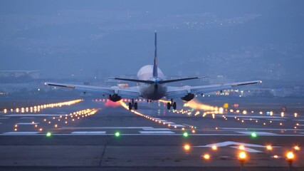 passenger aircraft landing at night, telephoto view from end of runway with straight perspective. br