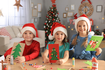 Wall Mural - Cute little children in Santa hats making beautiful Christmas greeting cards at home