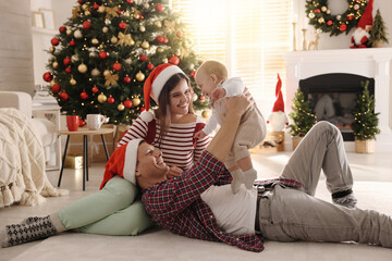 Wall Mural - Happy family with cute baby on floor in room decorated for Christmas