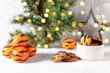 Wall Mural - orange cookies with black stripes in bowl and fir tree branches. Christmas dessert. Concept for children new year