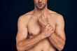 © Roman - Handsome young bearded man isolated. Cropped image of topless muscular man is standing on dark blue background. Man holding his wrist. Experiencing wrist pain