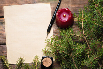 Blank paper page with copy space, quill pen, burning candle and fir tree branches on the wooden table background. New year plans template. Letter to the Santa Claus concept.