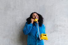 Happy Woman Talking On Retro Telephone In Front Of Gray Wall
