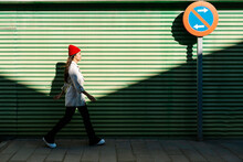 Young Woman Walking By Green Corrugated Wall