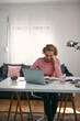 © astrosystem - Woman in 40s working from living room at home.