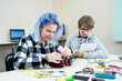 School students making robotic cars. Teenager girl and boy at robotics school makes robot managed from the constructor, child learns robot constructing.