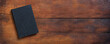 © Rawf8 - Closed old black book on a table. Blank cover notebook on wooden background, top view. Copy space