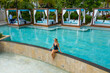 © AmazingAerialAgency - Aerial view of a beautiful girl relaxing at swimming pool in a luxury resort, Pointe de Flacq, Mauritius.
