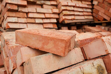 A Stack Of Red Clay Bricks In Rows Close Up. Lot Of Stacks Of Bricks On Construction Site
