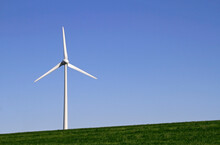 Wind Turbine On Green Grass Field Under Clear Blue Sky