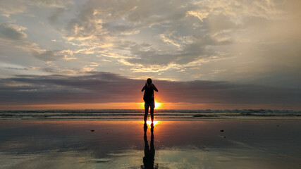 Wall Mural - A woman enjoy the sunset at Seminyak beach in Bali Indonesia.