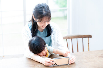 Wall Mural - スマホを子供にみせるアジア人（日本人）の綺麗なお母さん