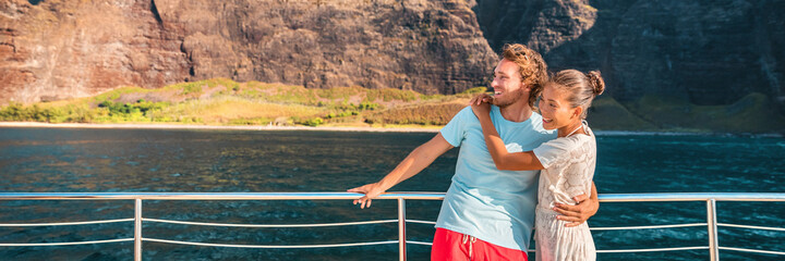 Wall Mural - Luxury cruise ship travel couple of tourists on yacht vacation happy looking to the side on background banner panoramic. Boat near Kauai island, Hawaii holiday. Asian woman, Caucasian man.