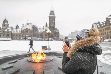ottawa travel tourist woman taking photo with phone of canadian parliament in ontario, canada. snowi