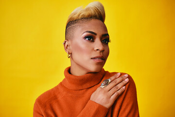 Portrait of a young woman with trendy hair, jewelry and sweater Against Yellow Background