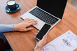 © LIGHTFIELD STUDIOS - cropped view of woman holding smartphone with blank screen near laptop, menu and coffee cup