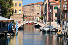 Venice In Italy With Footbridge Across Canal With Reflection. Old Houses. Romantic Old Architecture. Boats And Pedestrian Bridge Over Canal.